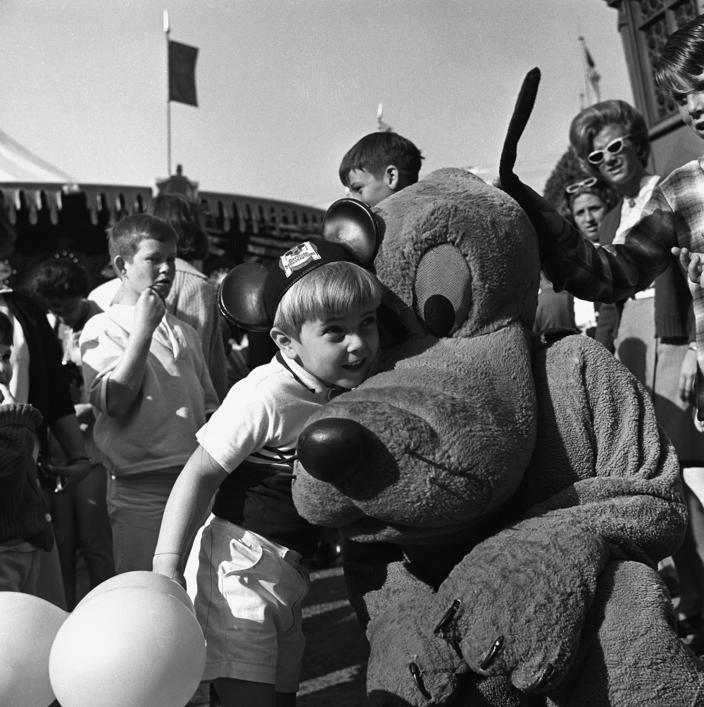 A young Disneyland guest hugs Pluto at the theme park in Anaheim, Calif., in 1964. (Disney via The New York Times)