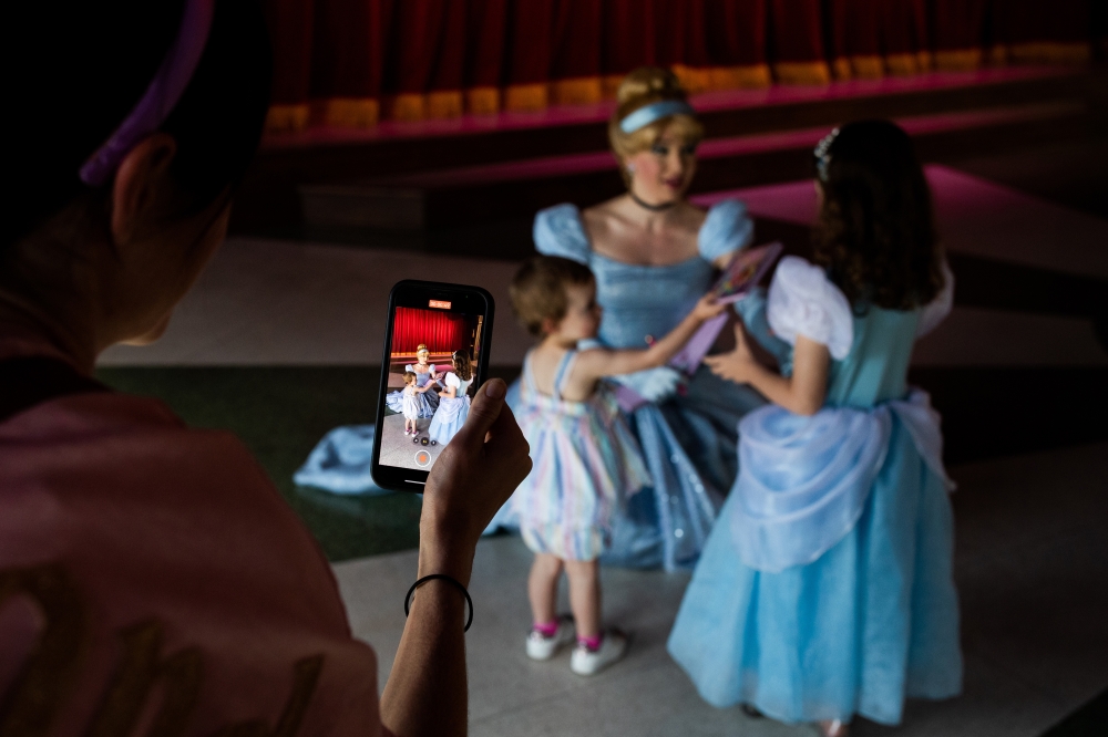 Kiandra Harman films Maggie Harman, left, and Sadie Harman as they greet Cinderella at Disneyland in Anaheim, Calif., where a two-year ban on character embraces ended on Monday, April 18, 2022. (Alex Welsh/The New York Times)
