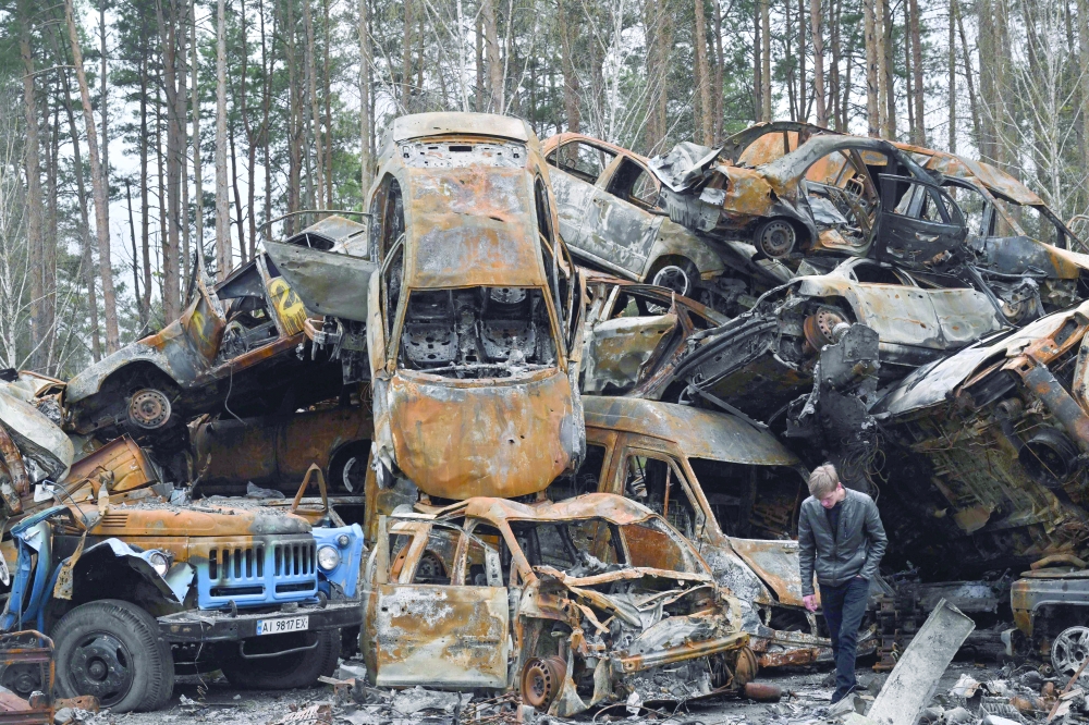 A man walks past destroyed and burned cars in Irpin during the Russian attack of Ukraine. - AFP

