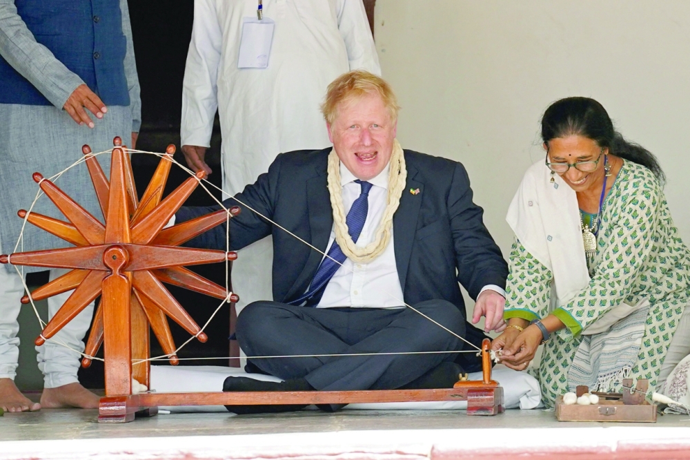 Britain's Prime Minister Boris Johnson spins khadi on a charkha or a spinning wheel during his visit at the Sabarmati Ashram also known as Gandhi Ashram in Ahmedabad on Thursday. - AFP