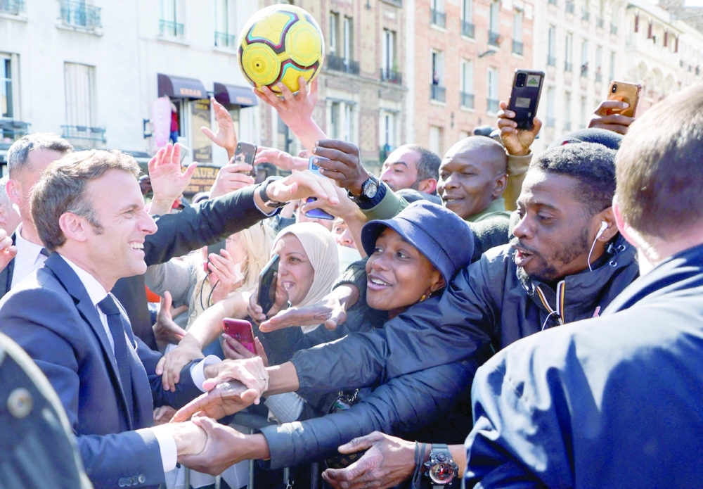 Emmanuel Macron holds hands of inhabitants during a campaign visit in Saint-Denis, a northern suburb of Paris, on Thursday. - AFP 