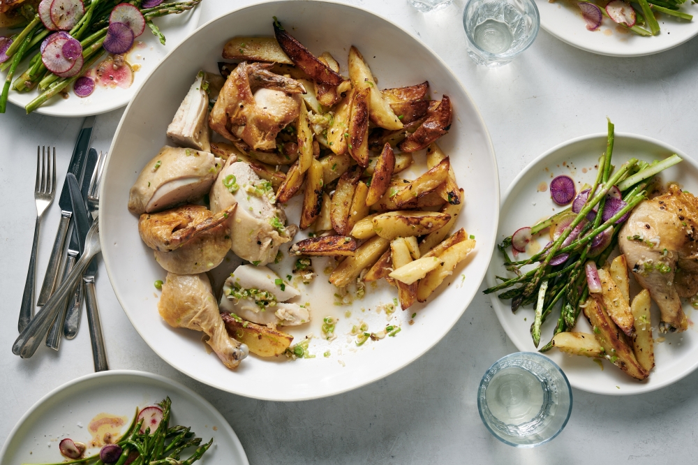 Roast chicken with green garlic, herbs and potatoes served with shaved asparagus and radish salad, in New York, March 31, 2022. Food styled by Simon Andrews. (David Malosh/The New York Times)
