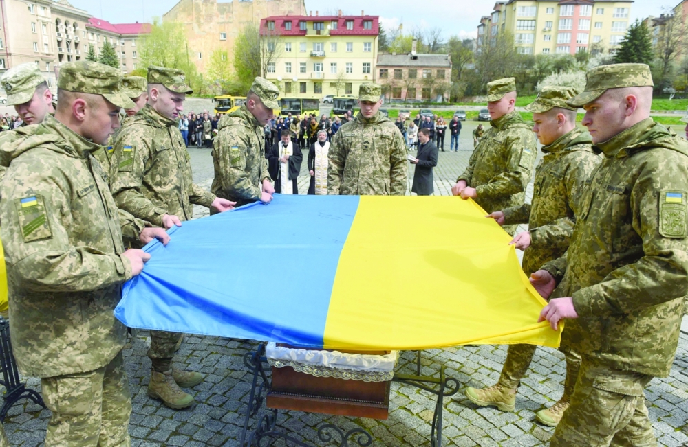 Servicemen drapes the coffin of Ukrainian serviceman who was killed during Russia's attack on Ukraine, with a Ukrainian flag during his funeral at Lychakiv cemetery in the western Ukrainian city of Lviv on Thursday. - AFP