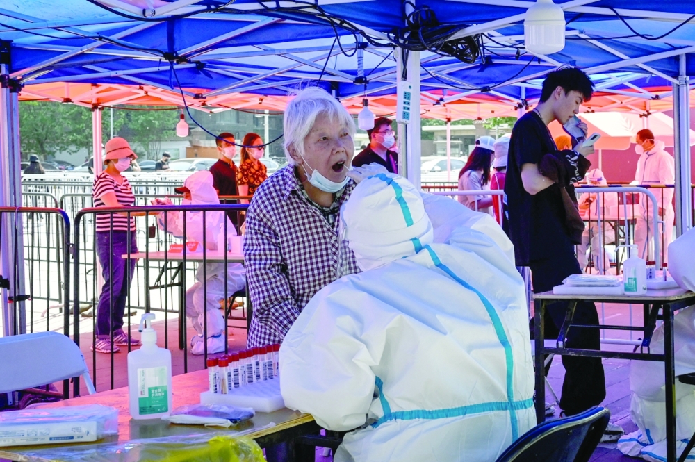 A health worker takes a swab sample from an elderly woman to be tested for Covid-19 at a makeshift testing site outside a museum along a street in Beijing on Wednesday. —  AFP