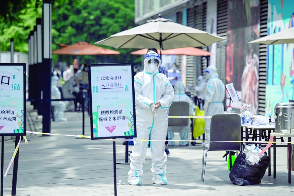 A health worker wearing personal protective equipment (PPE) stands at a Covid-19 coronavirus testing site outside a shopping mall in Beijing on May 5, 2022. (Photo by Jade GAO / AFP)
