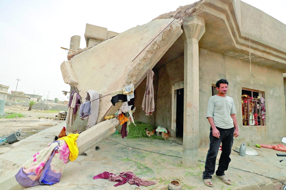 Iraqi father-of-five Issa al Zamzoum stands outside his damaged house in Habash. - AFP