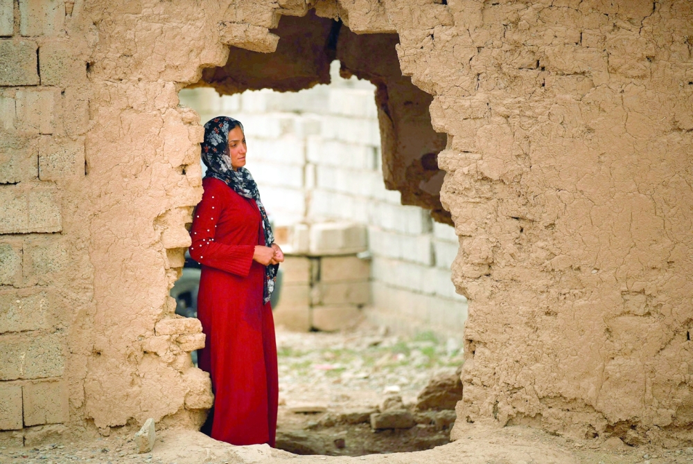 A woman looks out her damaged house in Habash. - AFP