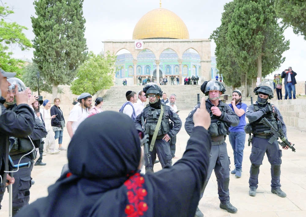 A Palestinian woman gestures as Israeli police accompany a group of Jewish visitors past the Dome of the Rock mosque at the Al Aqsa mosque compound in the Old City of Jerusalem on Thursday. - AFP 