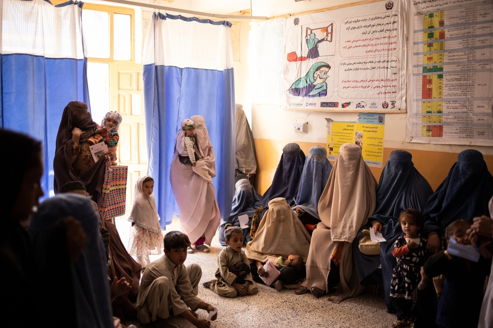 Women in Burqas and children await treatment at a World Food Program-supported health clinic in Kandahar, Afghanistan, Oct. 21, 2021. (Jim Huylebroek/The New York Times)