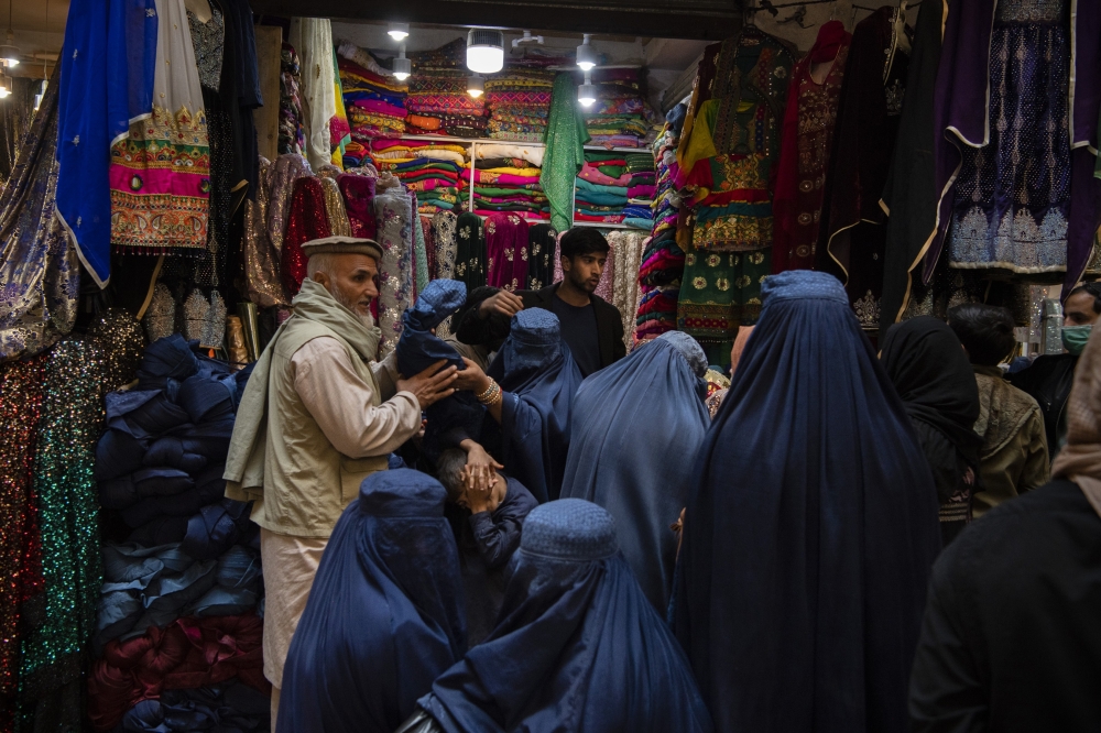 Women wearing burqas shop at a market in Kabul, in Nov. 2, 2021. (Kiana Hayeri/The New York Times)