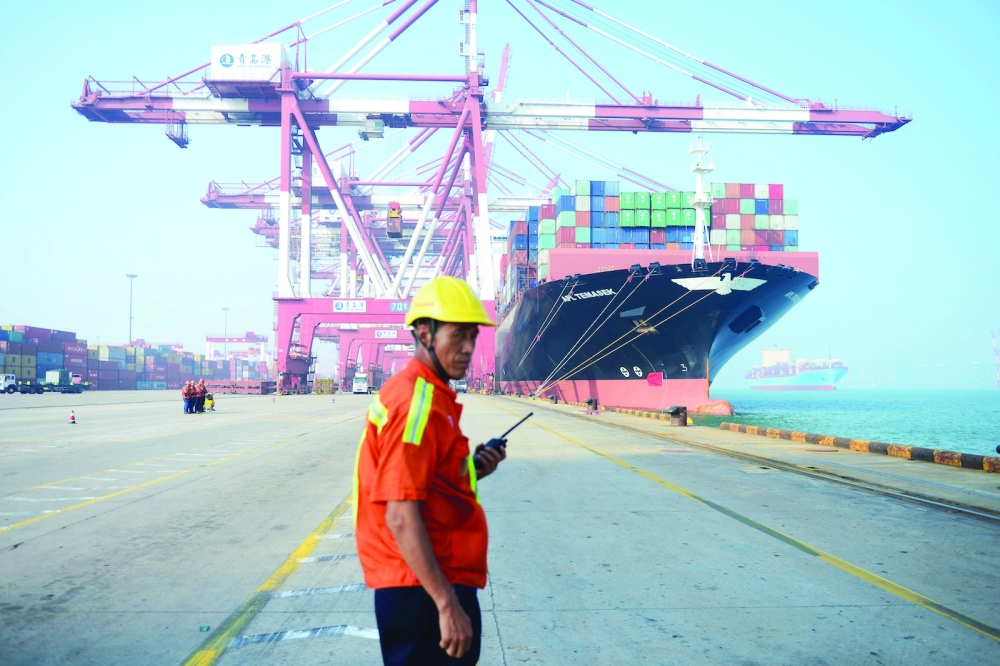 A Chinese worker looks on as a cargo ship is loaded at a port in Qingdao, eastern China's Shandong province. — AFP