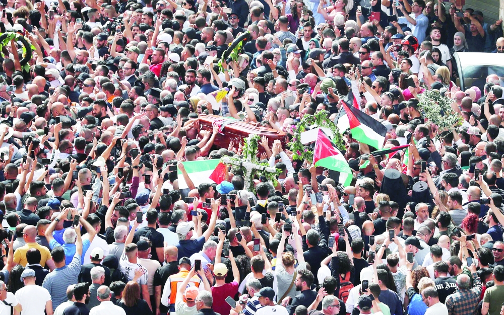 Palestinian mourners wave national flags as they carry the casket of Shireen Abu Akleh, during her funeral procession near Jaffa Gate, one of the main gates of the Old City of Jerusalem, on Friday. - AFP