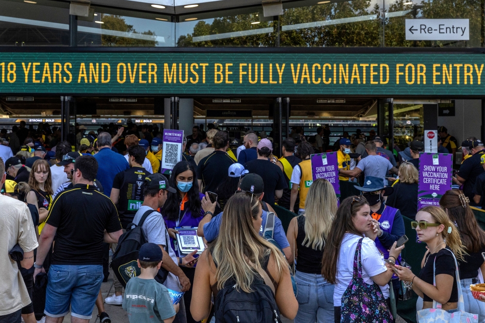 People use their phones to show their coronavirus vaccination certificates before entering the Melbourne Cricket Ground in Melbourne, Australia, March 27, 2022. (Asanka Brendon Ratnayake/The New York Times)