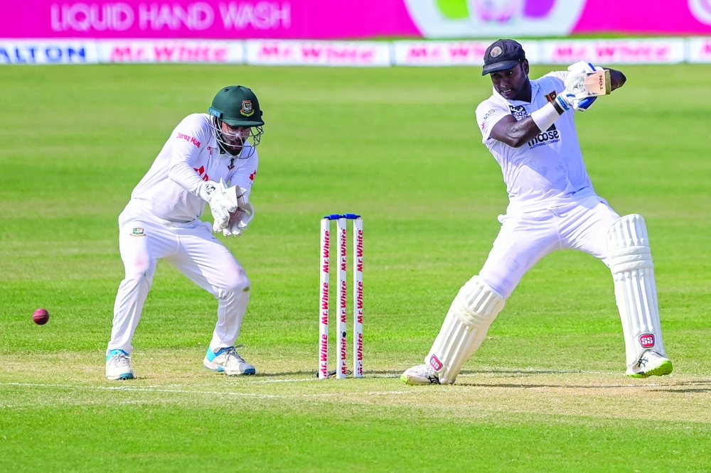 Sri Lanka's Angelo Mathews (R) plays a shot during the second day of the first Test cricket match between Bangladesh and Sri Lanka at the Zahur Ahmed Chowdhury Stadium in Chittagong on May 16, 2022. (Photo by Munir uz ZAMAN / AFP)

