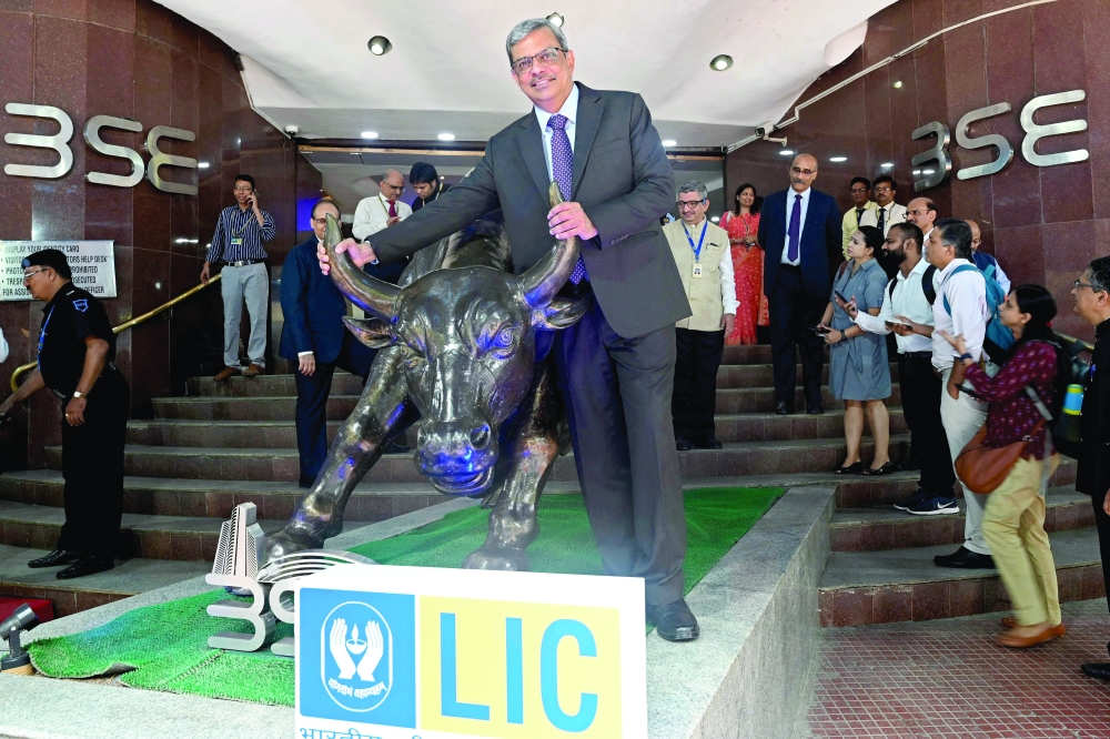 Mangalam Ramasubramanian Kumar (C), chairman of the Life Insurance Corporation of India (LIC) poses with the bronze statue of a bull at the Bombay Stock Exchange (BSE) in Mumbai, on Tuesday. — AFP