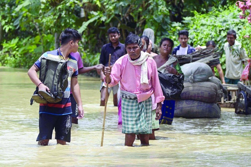 People wade through the flood waters in Nagaon district of India's Assam state. - AFP 