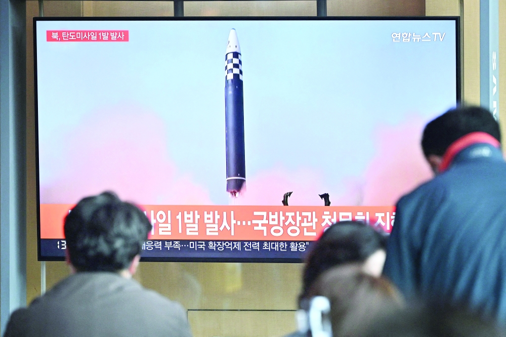 This file picture taken on May 4 shows people watching a television screen showing a news broadcast with file footage of a North Korean missile test, at a railway station in Seoul. - AFP  
