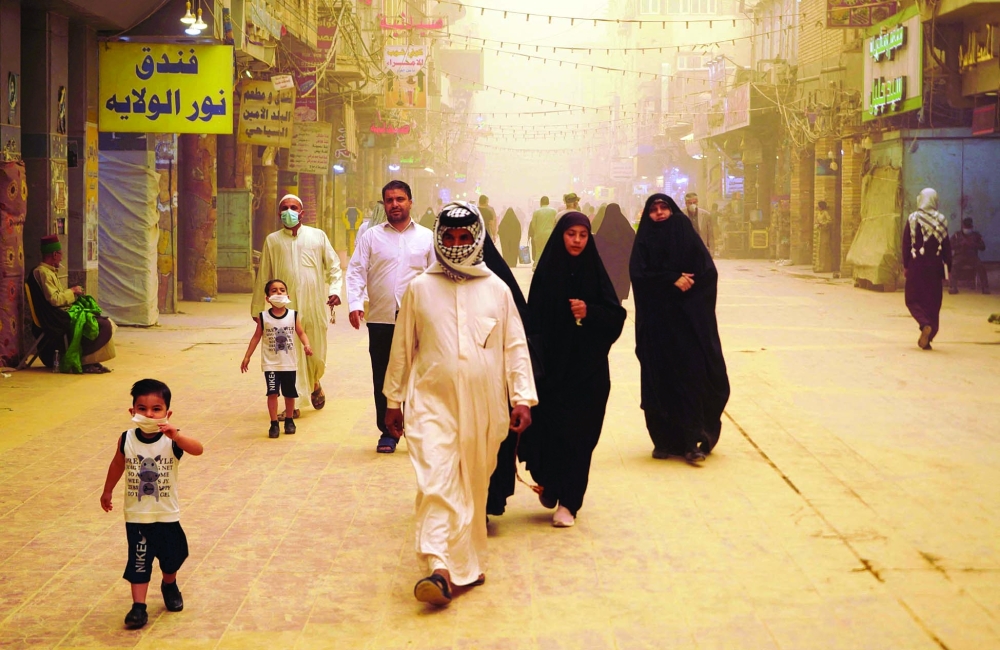 People walk during a sandstorm in Najaf, Iraq. Sandstorms have affected a total of 150 countries and regions, adversely impacting on the environment, health and the economy, the World Meteorological Organization said. -- AFP