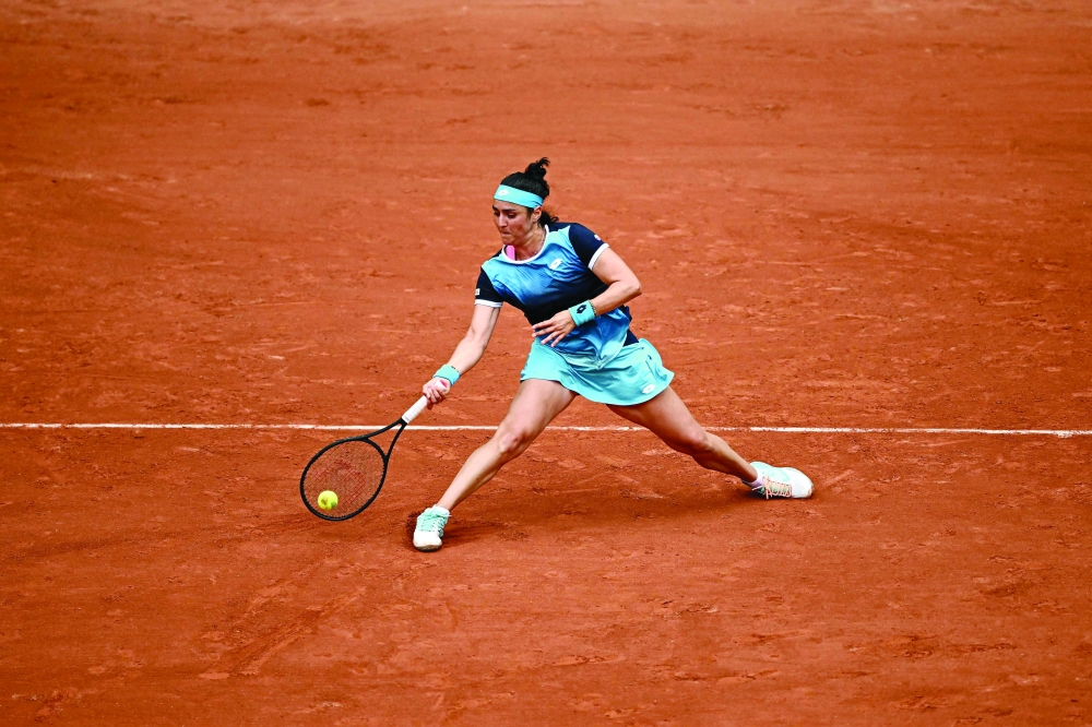Tunisia's Ons Jabeur plays a forehand return to Poland's Magda Linette during their women's singles match on day one of the Roland-Garros Open tennis tournament at the Court Philippe-Chatrier in Paris on May 22, 2022. (Photo by Anne-Christine POUJOULAT / AFP)

