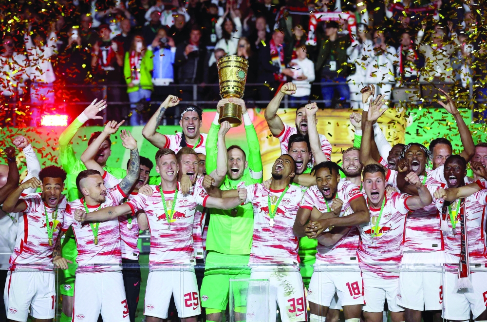 Leipzig's Hungarian goalkeeper Peter Gulacsi (C) lifts up the trophy as he celebrates with teammates after Leipzig won the German Cup (DFB Pokal) final football match between SC Freiburg and RB Leipzig at the Olympic Stadium in Berlin on May 21, 2022.  - DFB REGULATIONS PROHIBIT ANY USE OF PHOTOGRAPHS AS IMAGE SEQUENCES AND QUASI-VIDEO.

 (Photo by Ronny Hartmann / AFP) / DFB REGULATIONS PROHIBIT ANY USE OF PHOTOGRAPHS AS IMAGE SEQUENCES AND QUASI-VIDEO.


