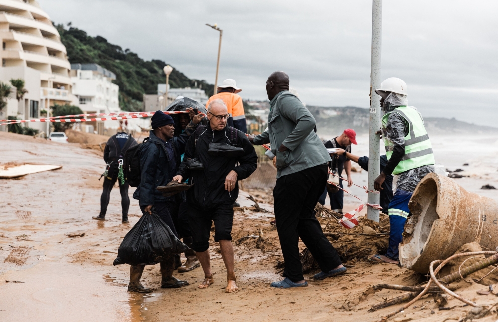 Local residents move to safety after they were trapped following heavy rains and winds in Umdloti north of Durban.  — AFP