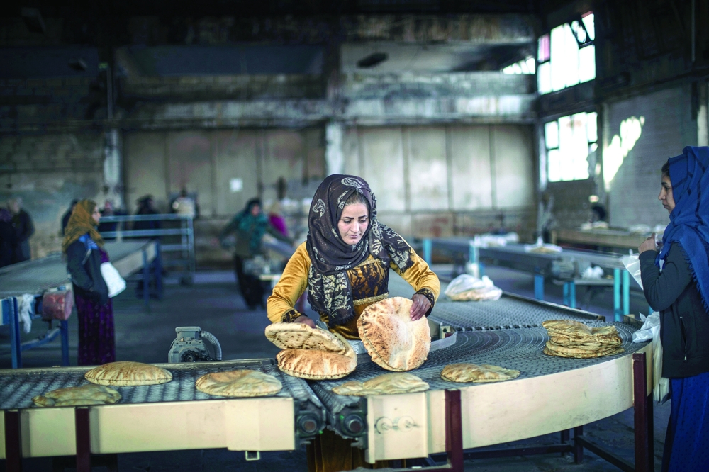 A woman works inside a bakery in Al Hasakah, Syria. The interruption of wheat exports from Ukraine and Russia is causing food prices to spiral and increasing global hunger, particularly in Africa and the Middle East. — The New York Times