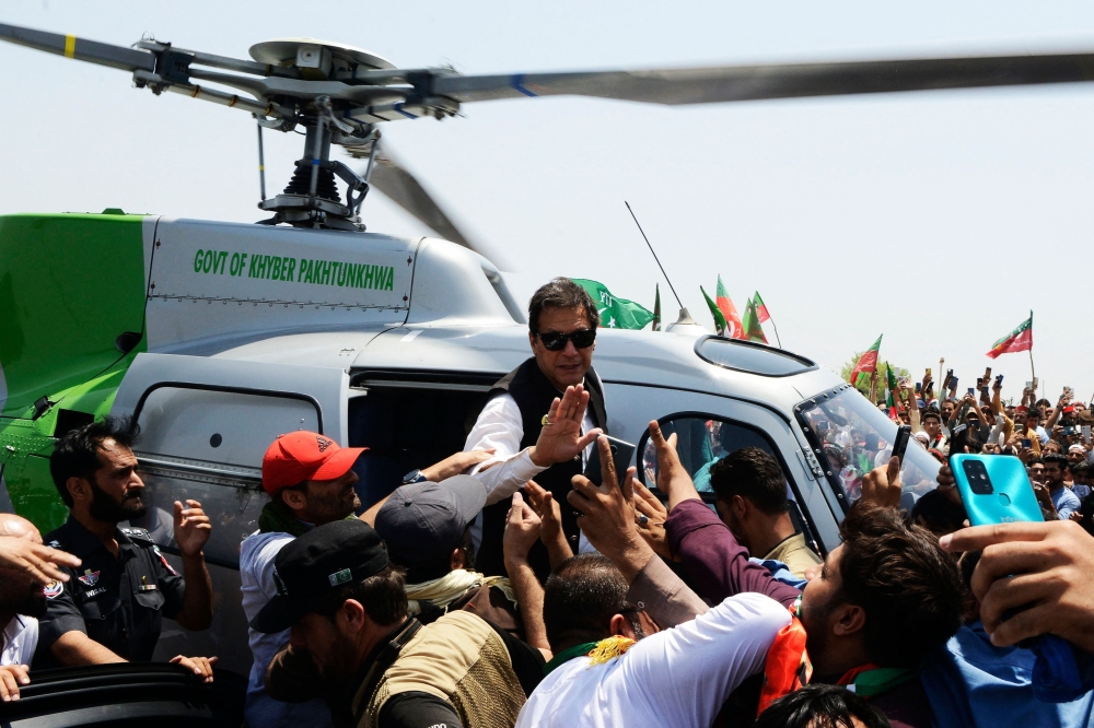 Pakistan's ousted prime minister Imran Khan waves to suporters upon arriving on a helicopter to lead a protest rally in Swabai on May 25, 2022.