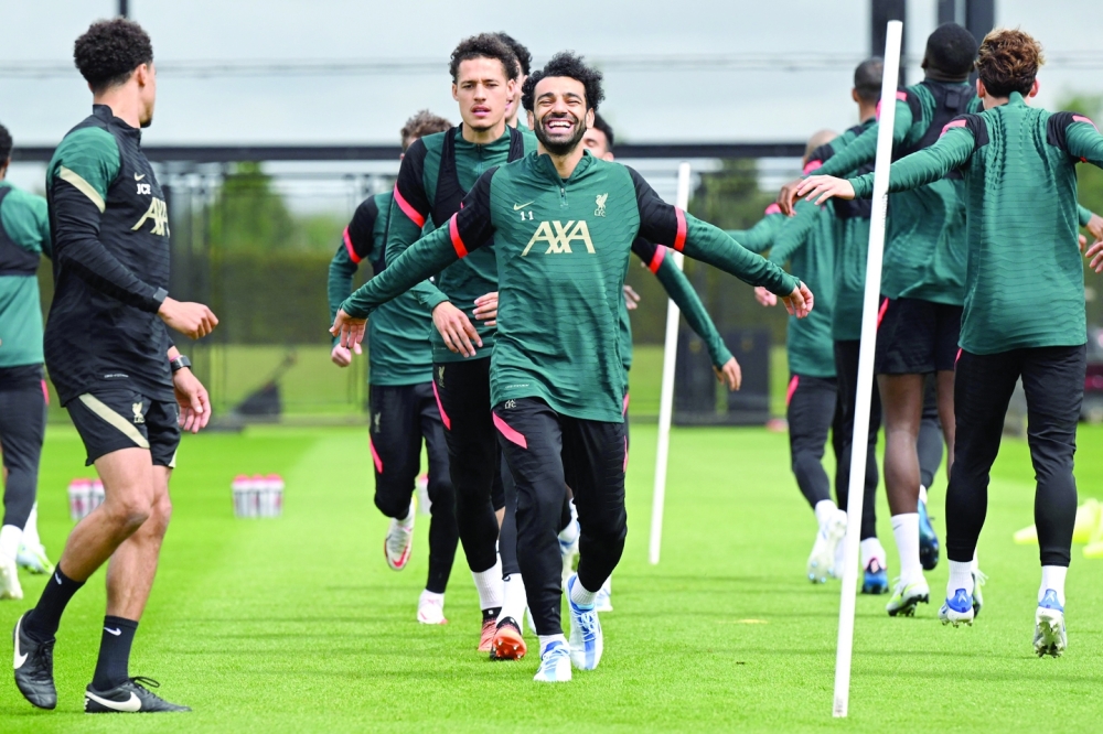 Liverpool's Egyptian midfielder Mohamed Salah (C) laughs as he runs with teammates during a training session at their training ground in Liverpool, northwest England, on May 25, 2022, ahead of their UEFA Champions League final football match against Real Madrid on May 28. (Photo by Paul ELLIS / AFP)

