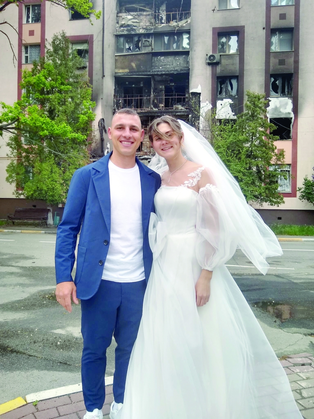 Mykhailo and Anastasia Dewberry pose for their wedding pictures in front of a damaged building, after getting married at a nearby pentecostal church, in Bucha, northwest of Kyiv on Thursday. - AFP 
