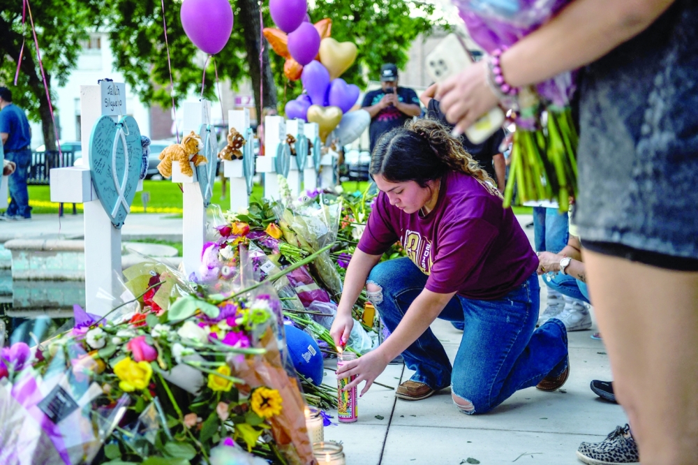 A woman lights a candle at a makeshift memorial outside Uvalde County Courthouse in Uvalde, Texas, on Thursday.   