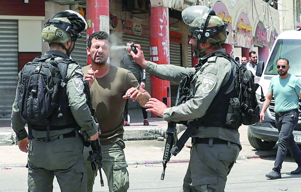 An Israeli border guard sprays pepper gas in the face of a Palestinian protester, during scuffles in the West Bank town of Hauwara, on Friday. - AFP