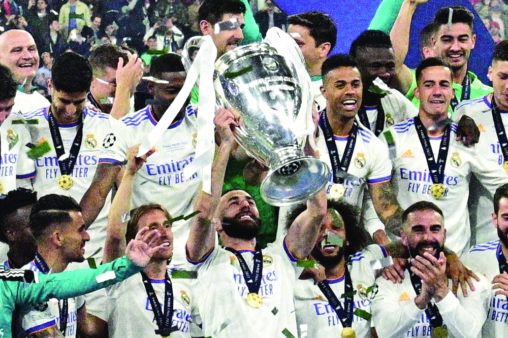 TOPSHOT - Real Madrid's French forward Karim Benzema (C) and his team-mates celebrate with the trophy after the UEFA Champions League final football match between Liverpool and Real Madrid at the Stade de France in Saint-Denis, north of Paris, on May 28, 2022. Real Madrid won the match 0-1. (Photo by JAVIER SORIANO / AFP)