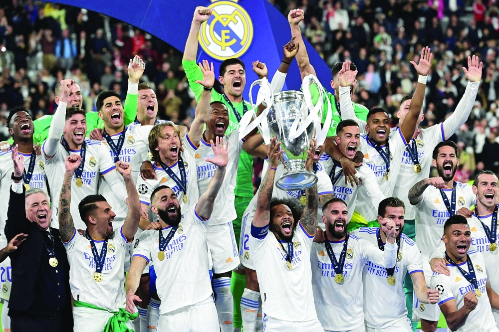 TOPSHOT - Real Madrid's Brazilian defender Marcelo (C) and his team-mates celebrate with the trophy after the UEFA Champions League final football match between Liverpool and Real Madrid at the Stade de France in Saint-Denis, north of Paris, on May 28, 2022. Real Madrid won the match 0-1. (Photo by JAVIER SORIANO / AFP)