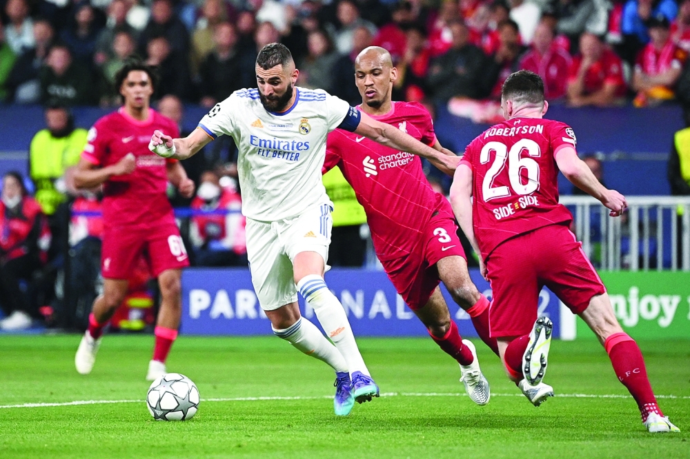 Real Madrid's French striker Karim Benzema (L) controls the ball as he is marked by Liverpool's Scottish defender Andrew Robertson (R) during the UEFA Champions League final football match between Liverpool and Real Madrid at the Stade de France in Saint-Denis, north of Paris, on May 28, 2022.  (Photo by Anne-Christine POUJOULAT / AFP)

