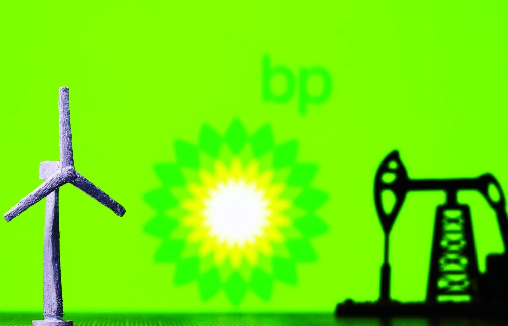A 3D printed windmill and oil pump jack are seen in front of displayed BP (British Petroleum) logo in this illustration picture. — AFP