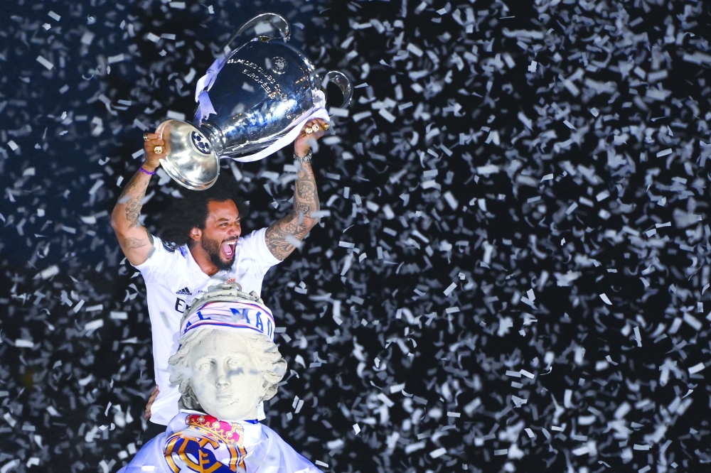 TOPSHOT - Real Madrid's Brazilian defender Marcelo lifts their trophy ontop of the statue of Greek goddess Cybele on May 29, 2022 at the Cibeles square in Madrid, a day after beating Liverpool in the UEFA Champions League final in Paris.  Real Madrid claimed a 14th European Cup as Vinicius Junior's goal saw them beat Liverpool 1-0 in the Champions League final at the Stade de France amid chaotic scenes yesterday. (Photo by GABRIEL BOUYS / AFP)

