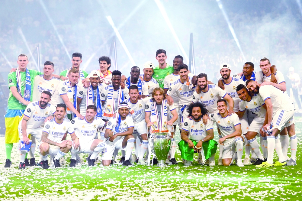 TOPSHOT - Real Madrid's players pose with their trophy during the club's celebration of their 14th European Cup at the Santiago Bernabeu stadium in Madrid on May 29, 2022, a day after beating Liverpool in the UEFA Champions League final in Paris.  Real Madrid claimed a 14th European Cup as Vinicius Junior's goal saw them beat Liverpool 1-0 in the Champions League final at the Stade de France amid chaotic scenes yesterday. (Photo by OSCAR DEL POZO / AFP)

