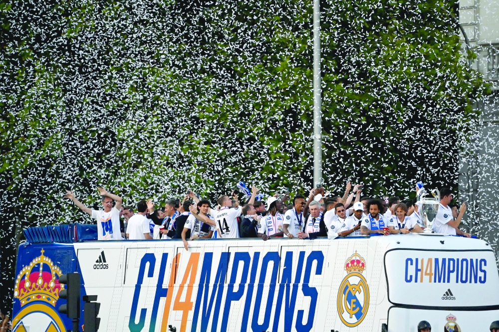 Real Madrid players celebrate with their trophy as they wave from an open-top bus during a parade through the streets of Madrid on May 29, 2022, a day after beating Liverpool in the UEFA Champions League final in Paris.  Real Madrid claimed a 14th European Cup as Vinicius Junior's goal saw them beat Liverpool 1-0 in the Champions League final at the Stade de France amid chaotic scenes yesterday. (Photo by GABRIEL BOUYS / AFP)

