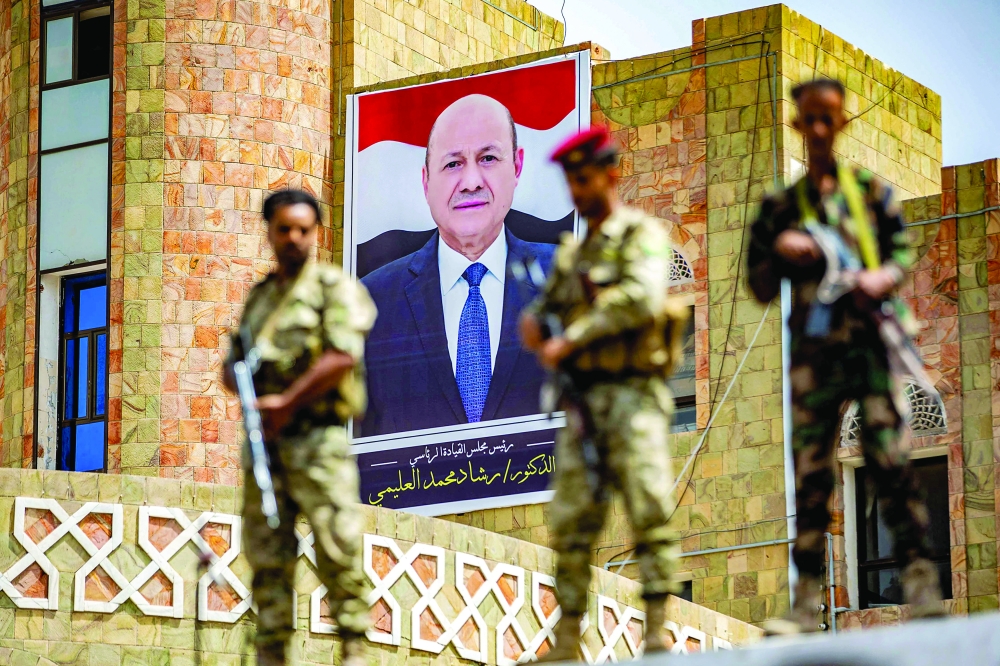 In this file photo taken on May 25, soldiers loyal to the Aden-based Yemeni government stand guard before a poster showing the chairman of the presidential council Rashad al Alimi, while on guard duty during a demonstration demanding the end of a years-long siege imposed by the Ansar Allah fighters on the third city of Taez. - AFP
