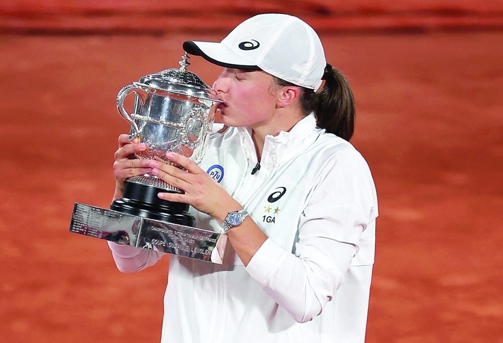 Poland's Iga Swiatek poses with the trophy after winning against US' Coco Gauff. -- AFP