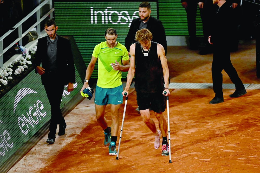 Germany's Alexander Zverev (R) walks with crutches on the court after being injured during his men's semifinal singles match against Spain's Rafael Nadal. -- AFP