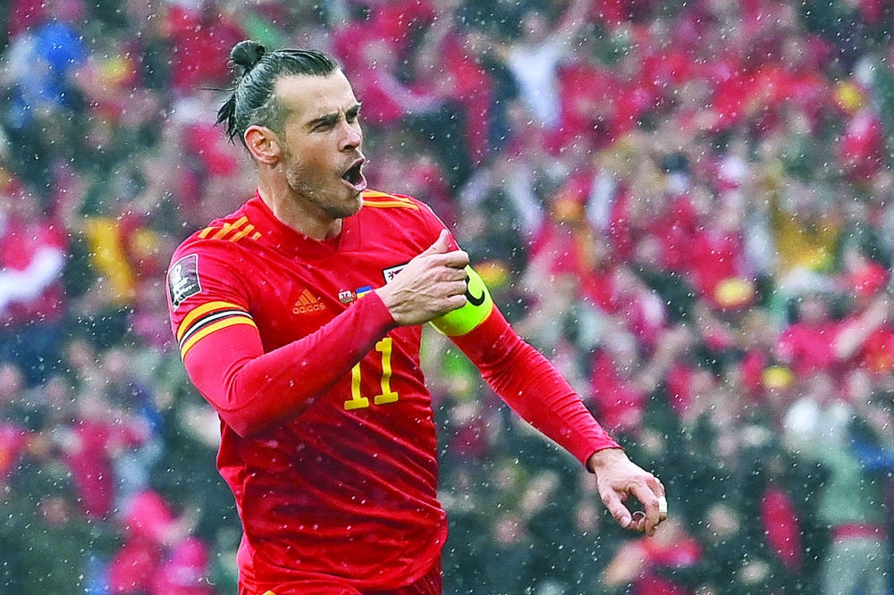 TOPSHOT - Wales' striker Gareth Bale celebrates after hitting a free kick and Ukraine scoring an own goal opening the score during the FIFA World Cup 2022 play-off final qualifier football match between Wales and Ukraine at the Cardiff City Stadium in Cardiff, south Wales, on June 5, 2022.  (Photo by Paul ELLIS / AFP)

