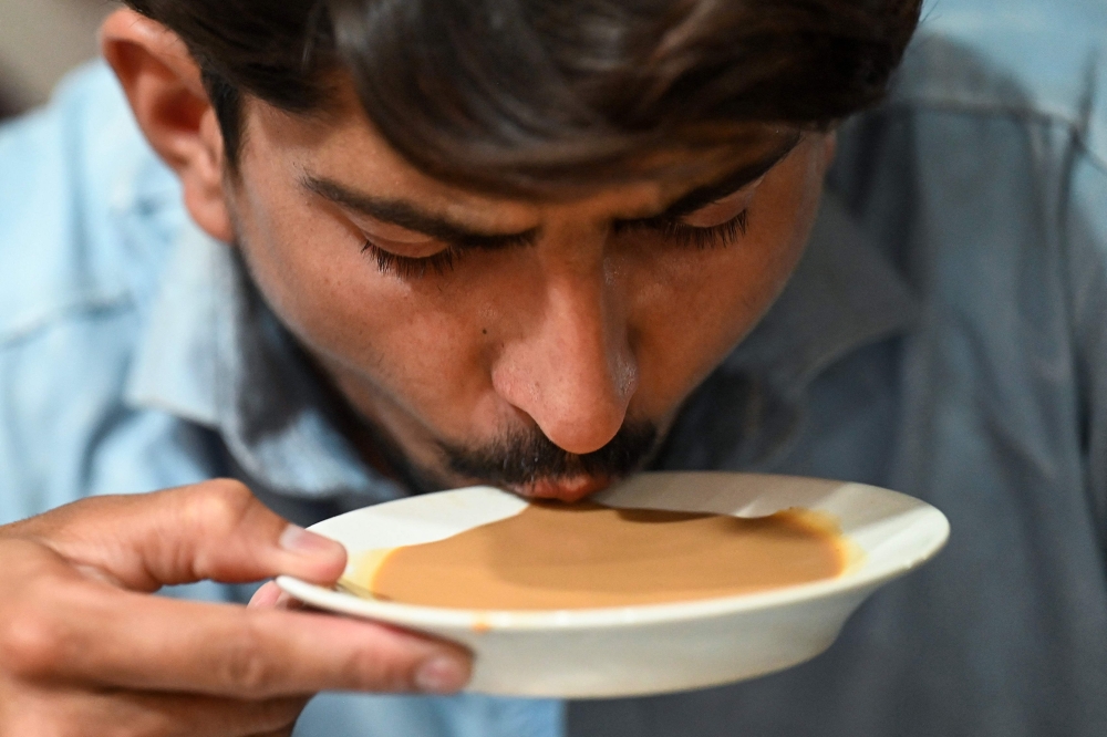 A man drinks tea from a saucer at a restaurant in Islamabad on June 15, 2022. 