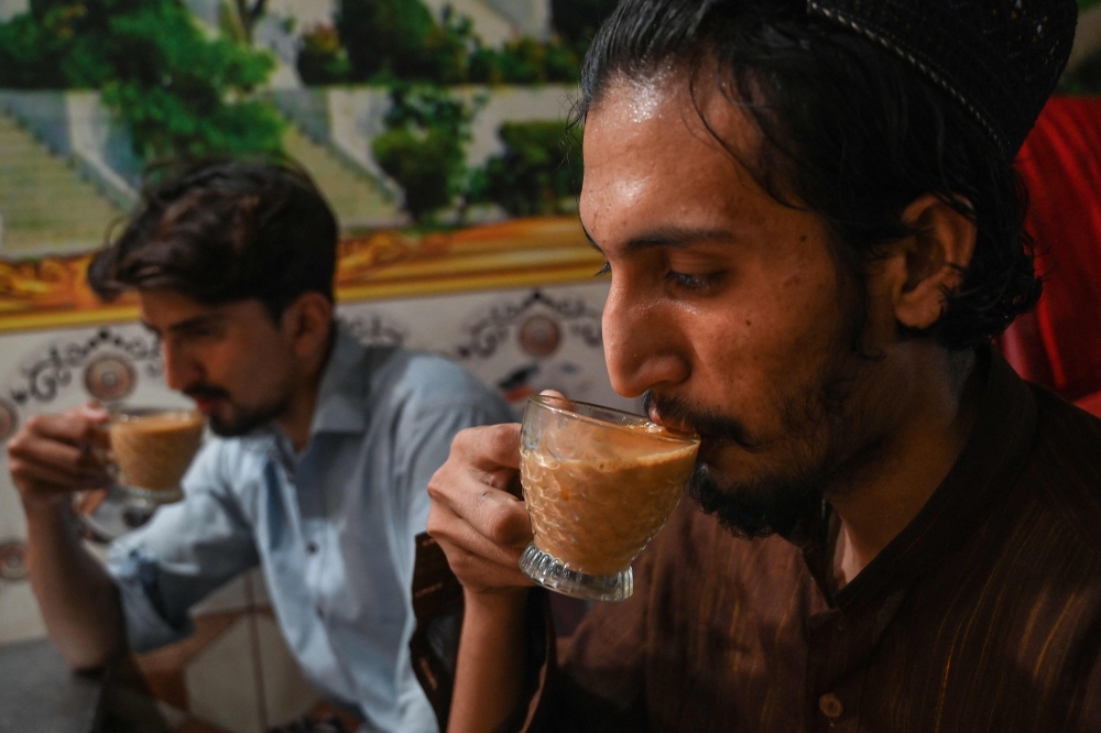A man drinks tea from a saucer at a restaurant in Islamabad on June 15, 2022. 