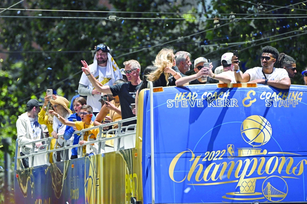Head coach Steve Kerr (C) waves with coaching staff from a double decker bus. -- AFP