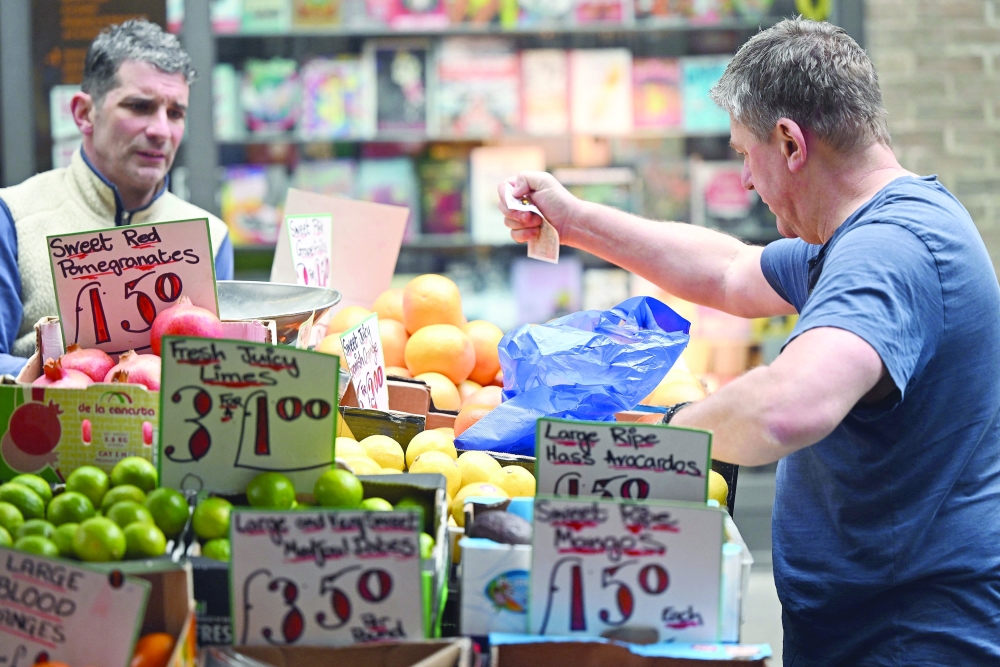 A man buy fruits at a fruit stand in central London. — AFP