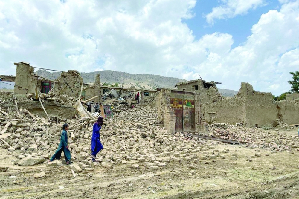 People walk amidst the rubble of damaged houses following a 5.9-magnitude earthquake in Bermal district on Thursday. — AFP