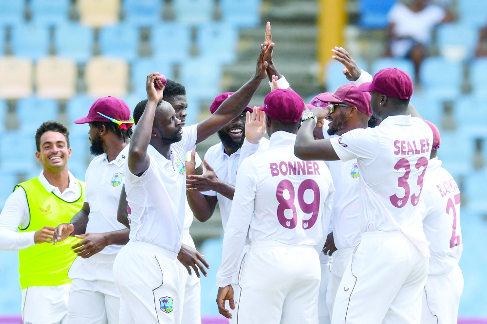 Kemar Roach and team-mates, of West Indies, celebrate his 250th Test wicket. -- AFP