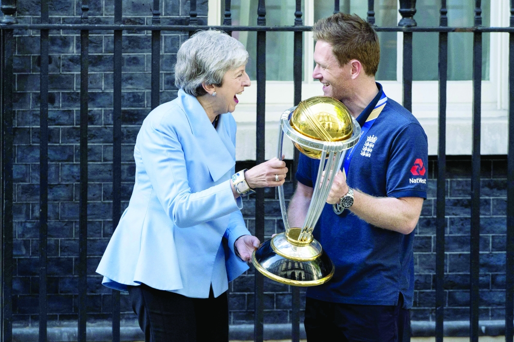 In this file photo taken on July 15, 2019 Britain's Prime Minister Theresa May (L) shares a joke with England's captain Eoin Morgan (R) as they hold the World Cup trophy outside 10 Downing Street. -- AFP