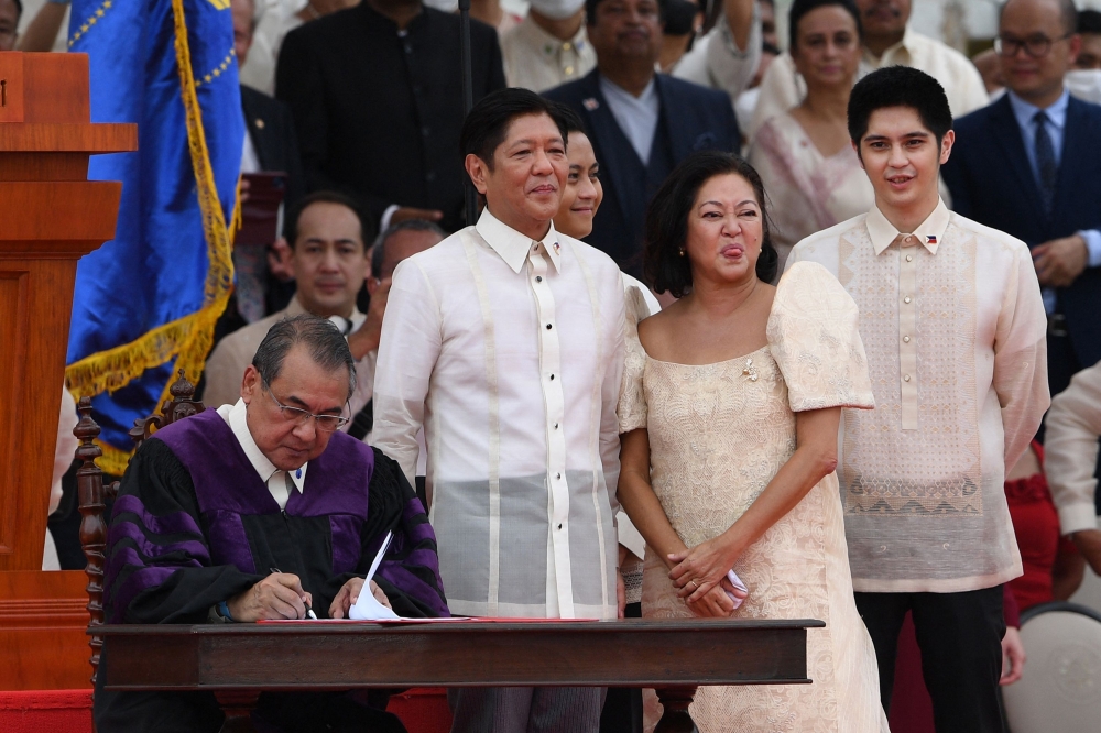 New Philippine President Ferdinand Marcos Jr. (C) and wife Louise look on as Supreme Court chief Justice Alexander Gesmundo (L) signs the oath of office after the swearing-in ceremony of the new president at the National Museum in Manila on June 30, 2022.